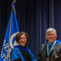 Provost Mili smiles and shakes hands with man